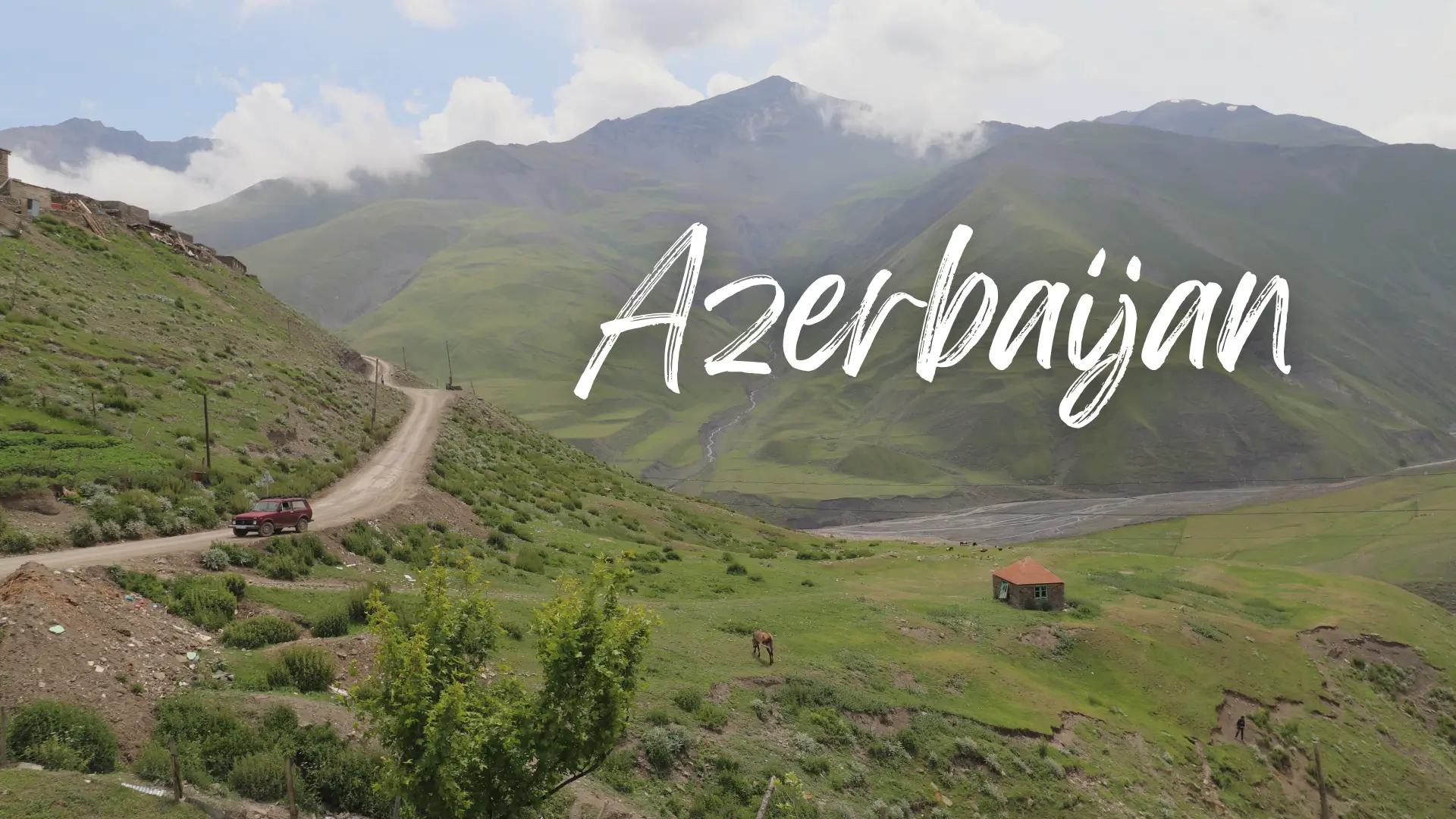 rolling green hills in Xinaliq, Azerbaijan has a dirt road with a 4x4 vehicle, a horse and a small brick house - azerbaijan travel guide