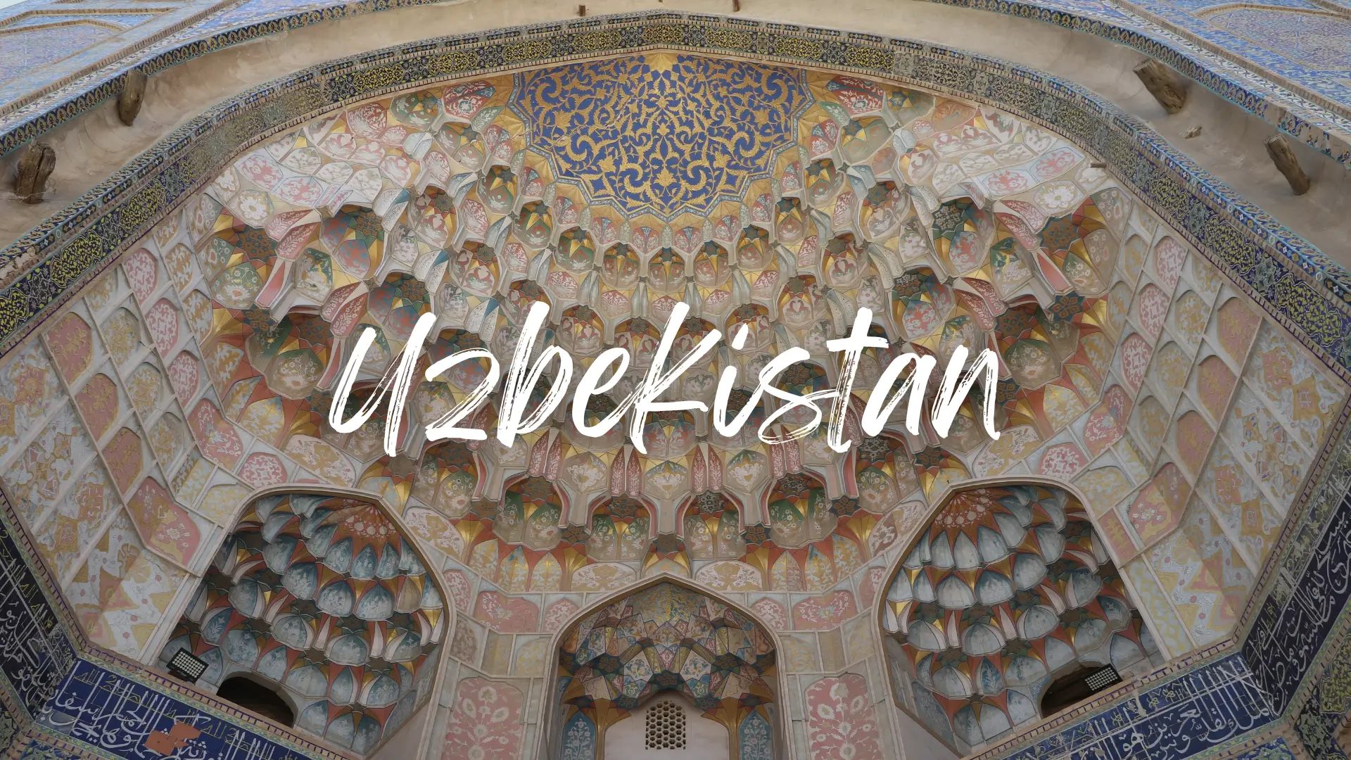 a view up into the decorative archway of a historic building of Uzbekistan's Silk Road cities. The archway if intricately carved and painted in bright colours. Uzbekistan travel guide
