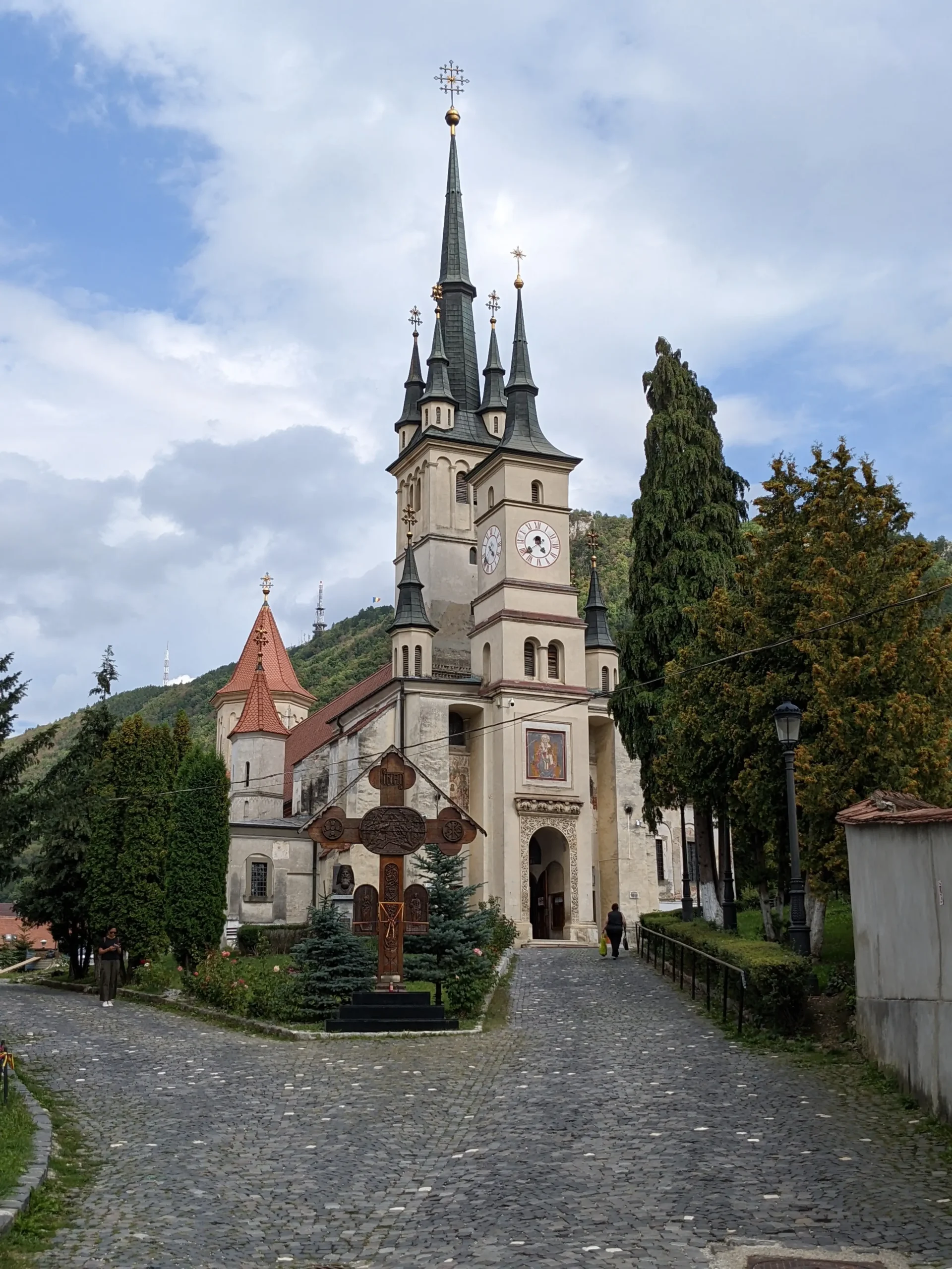 Biserica Sfântul Nicolae, Brasov Biserica Sfântul Nicolae - a tall narrow church with pointy spires is surrounded by greenery in Brasov, Romania