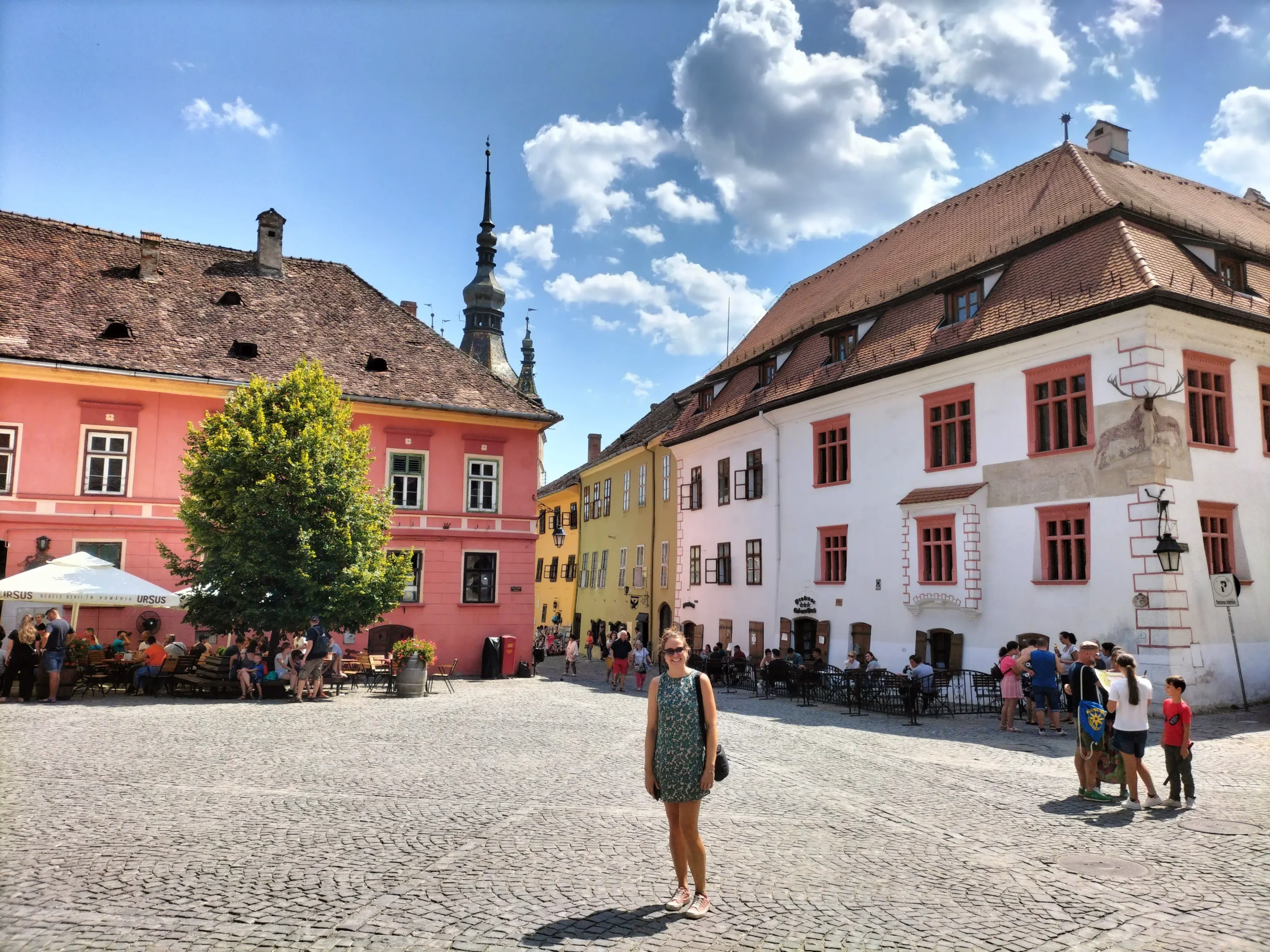 a cobbled square is surrounded by colourful medieval buildings in Sighisoara, Romania