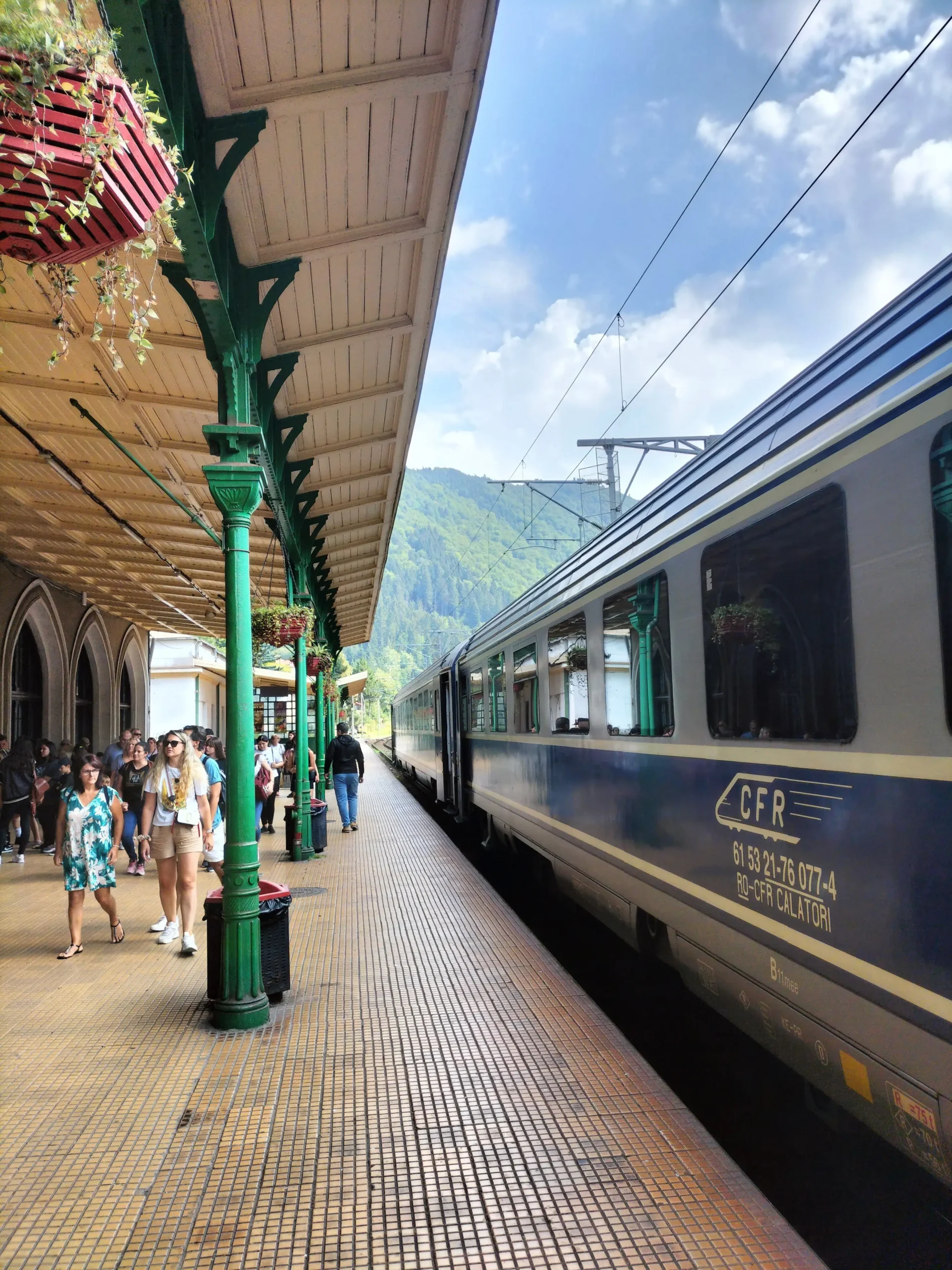 a blue and white train pulls into a Romanian station - Bucharest to Brasov train