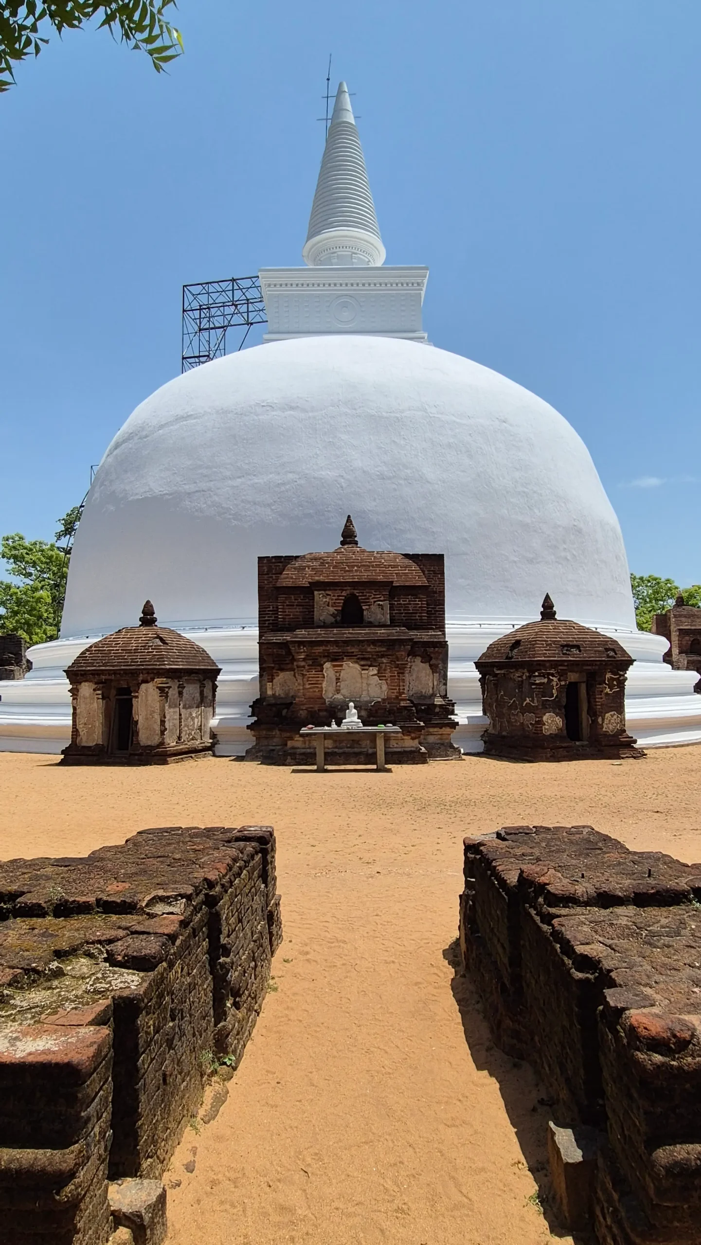 Polonnaruwa, Sri Lanka a bright white painted bell-shaped dagoba has three small brick houses for buddha statues in Polonnaruwa, Sri Lanka